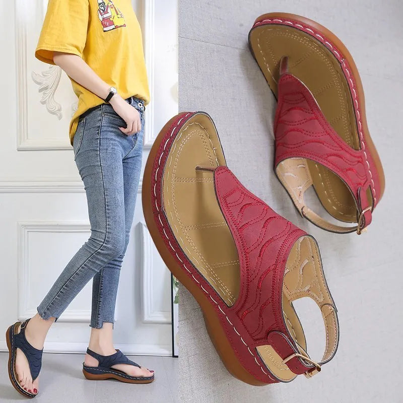 Women's red wedge heel sandals with an adjustable buckle strap on a plain background.