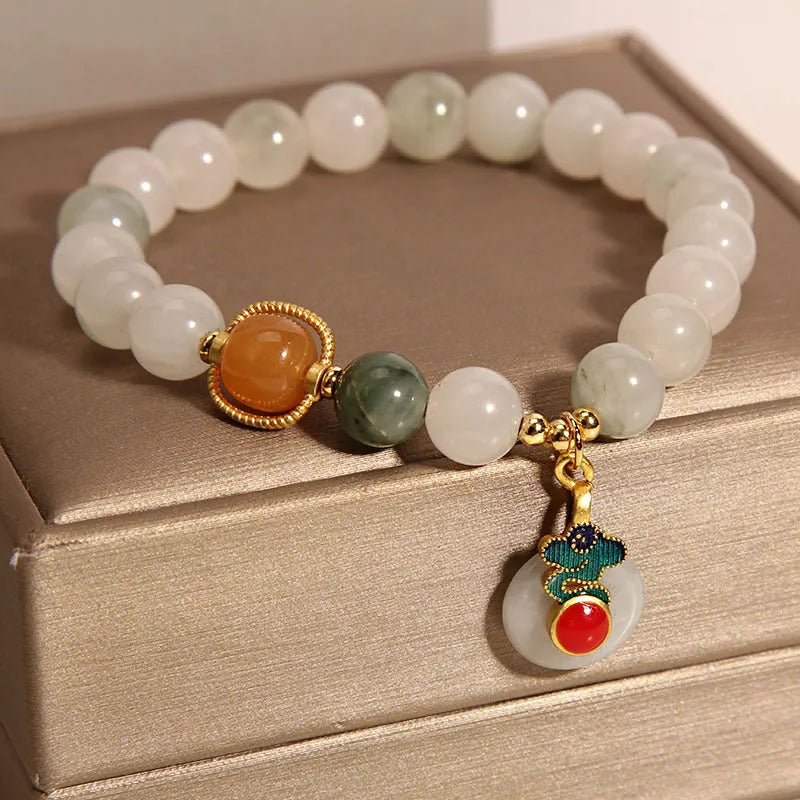 Women's ice jade bracelet with xiangyun pattern, peace buckle, and pearl accents on a white background.
