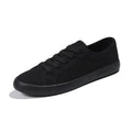 All-black women's low-top canvas shoes with lace-up front and flat rubber sole.