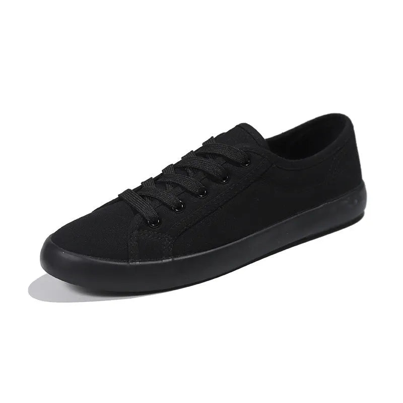 All-black women's low-top canvas shoes with lace-up front and flat rubber sole.