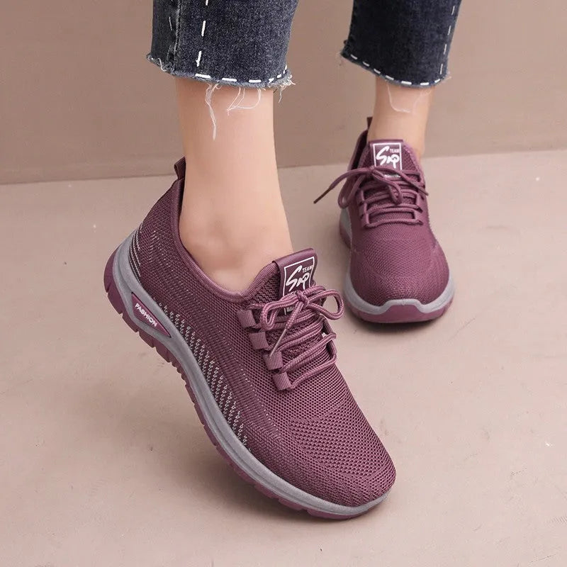Women's black casual sneakers with mesh upper, cross straps, and round toe on a rubber sole.