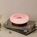 Rechargeable donut touch table lamp in custard, green, orange, or pink with three colour modes and charging cable