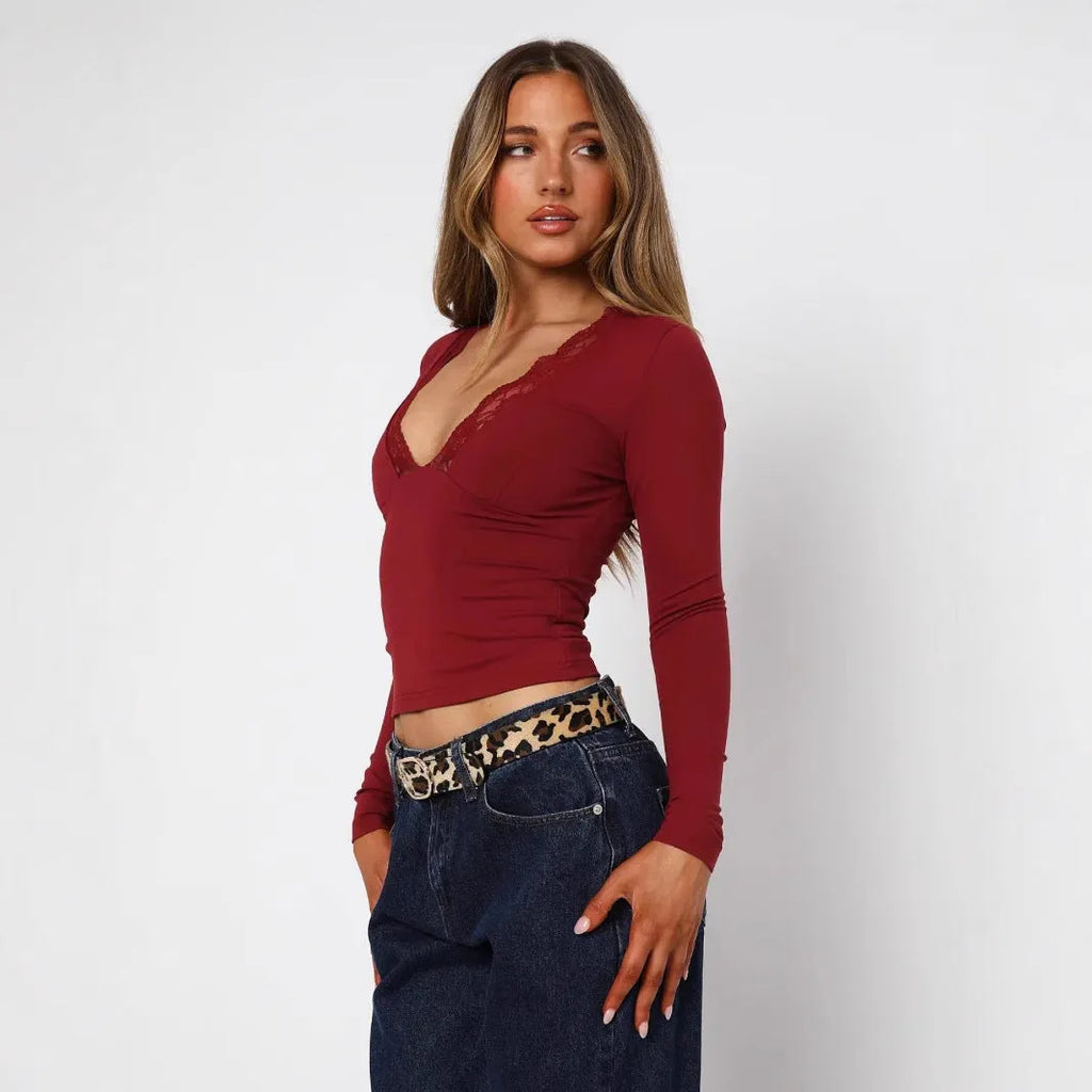 Women's slim-fit long sleeve black top with lace flower detail on front.