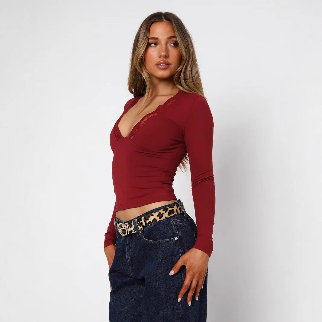 Women's slim-fit long sleeve black top with lace flower detail on front.