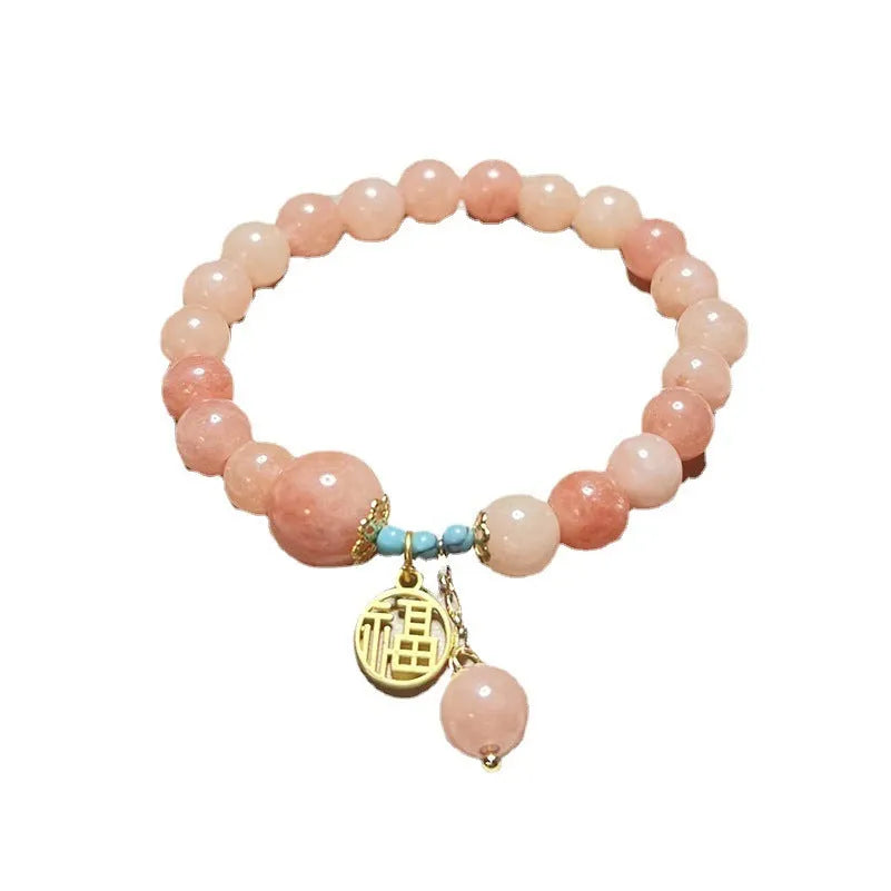 Close-up of a pink natural stone set within a simple silver-toned alloy women's bracelet.