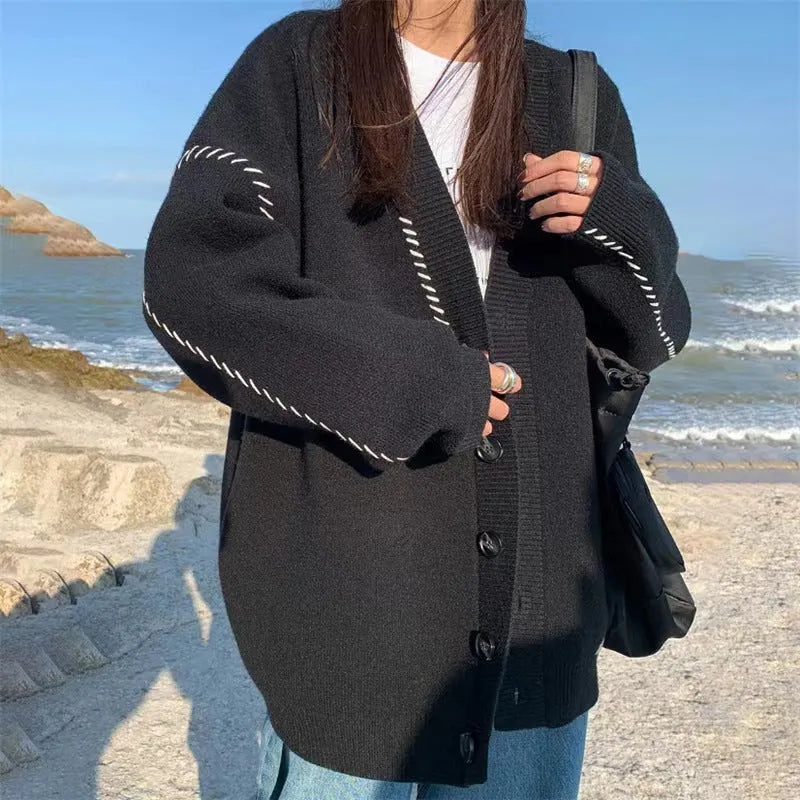 Women's loose-fit knitted cardigan coat in black, shown as a long-sleeve layering piece.