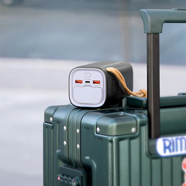 Black portable power bank with digital display, showing solar panel and car charging cables.