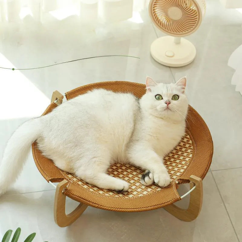 Brown woven rattan raised cot bed for cats and small dogs on a wooden floor
