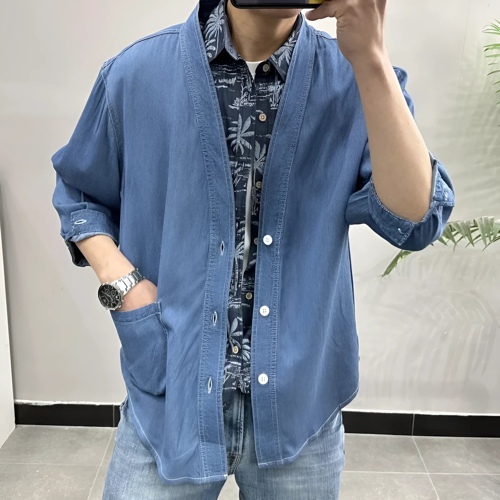 Men's dark blue V-neck denim coat with three-quarter sleeves showing loose fit and pocket detail