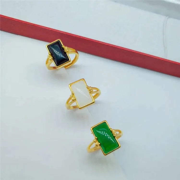 A gold-plated brass ring with an adjustable band and a central green artificial gemstone, in a national style.