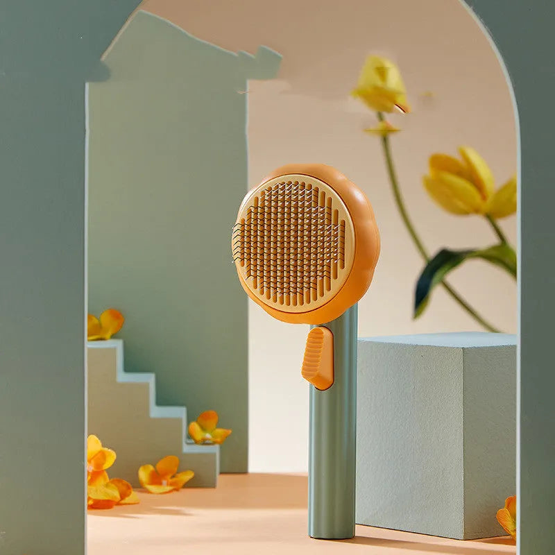 Pumpkin coloured pet grooming brush with curved stainless steel needles and a hand-held plastic handle.