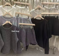 Woman wearing a loose grey long sleeve knitted sweater and matching wide leg shorts set.
