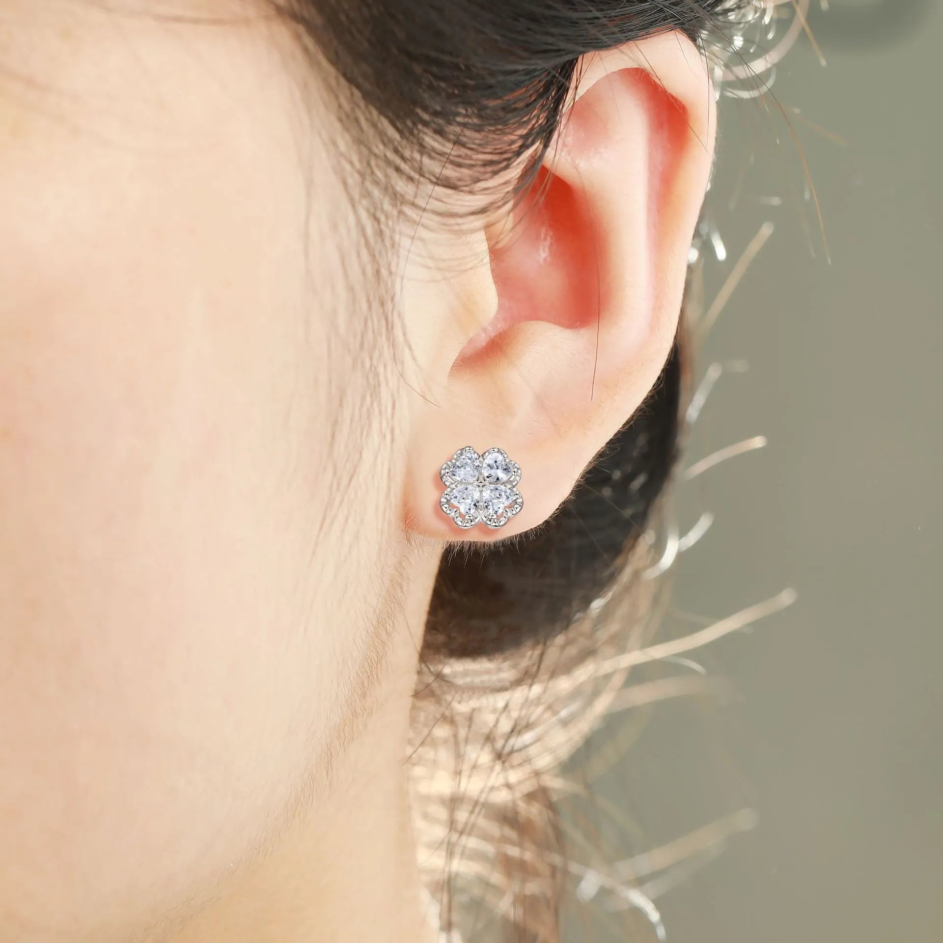 A pair of 925 silver earrings with a four-leaf clover charm and heart-shaped zircon stones in white gold colour.