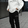 Man wearing a grey letter-print hoodie and matching joggers from a winter sports set.