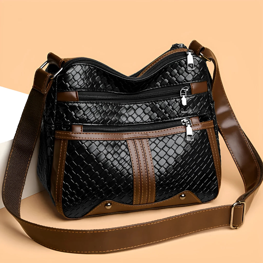 Horizontal square messenger bag with multiple compartments and woven shoulder strap in black with brown trim