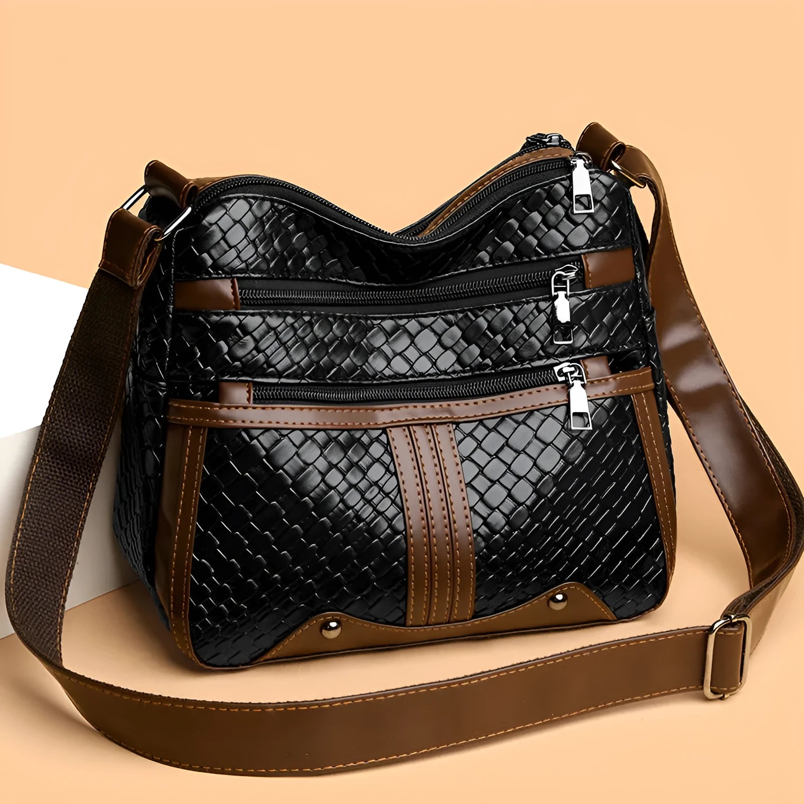 Horizontal square messenger bag with multiple compartments and woven shoulder strap in black with brown trim