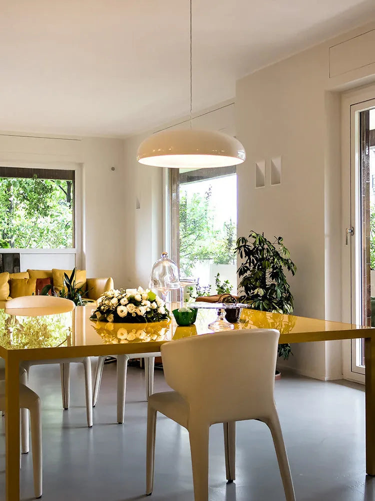 Modern Danish orange iron pendant lamp with adjustable cable over a restaurant dining table.