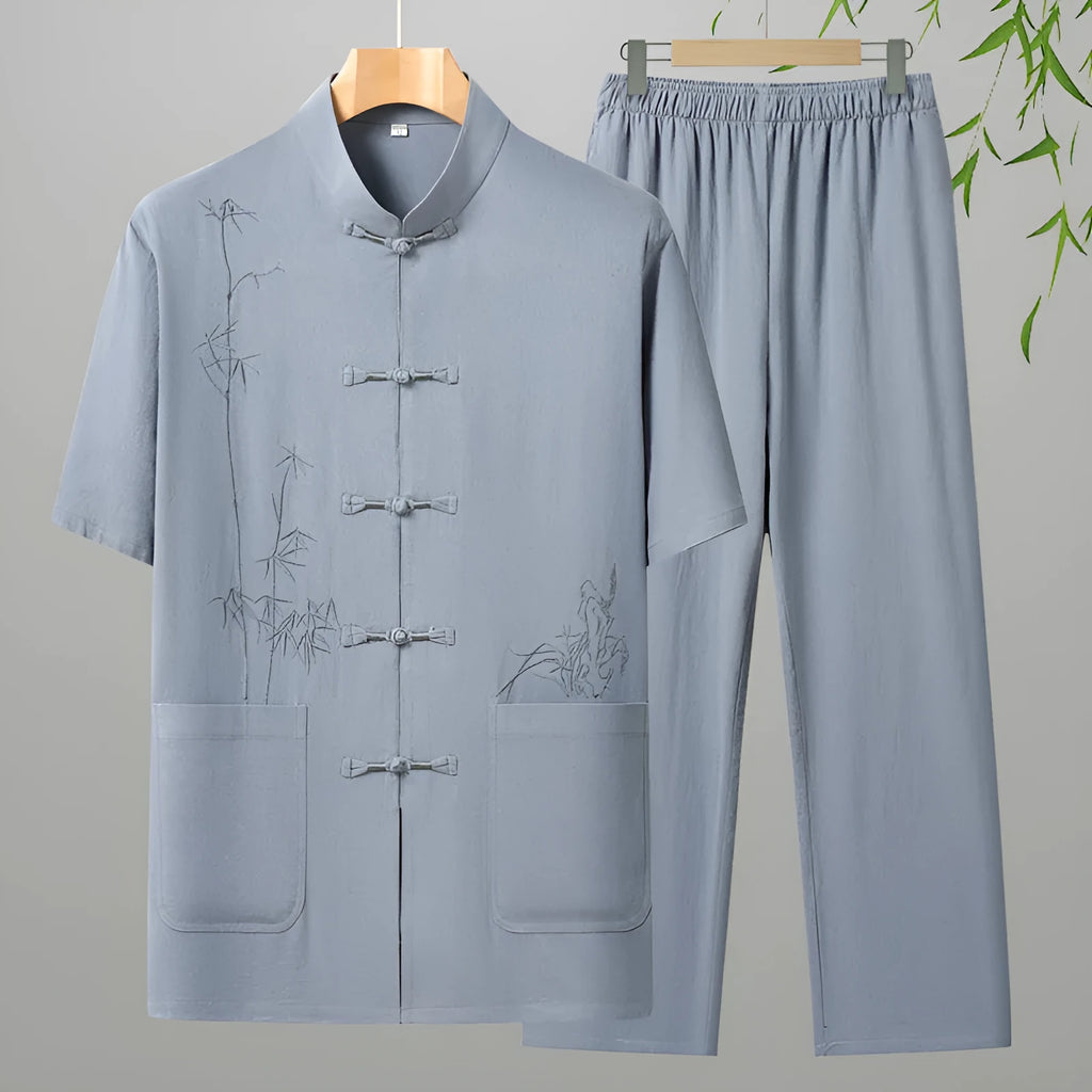 Elderly man wearing a grey cotton short-sleeved leisure suit with matching trousers.