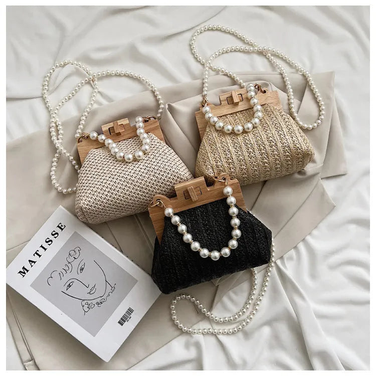 Women's woven straw shoulder bag with pearl chain detail showing horizontal square shape and internal compartments