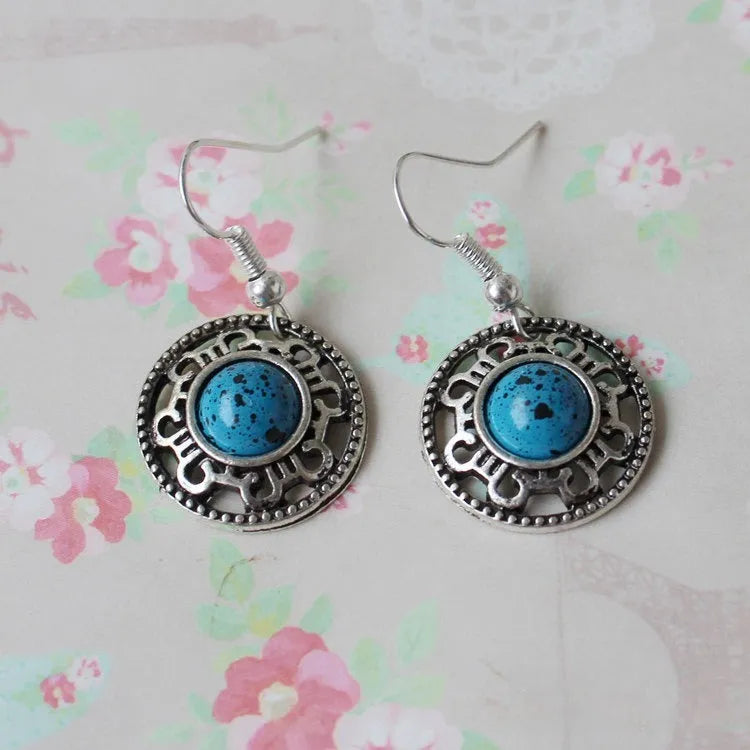 Handmade Miao-inspired silver and turquoise geometric flower disk earrings in black, blue, and red.