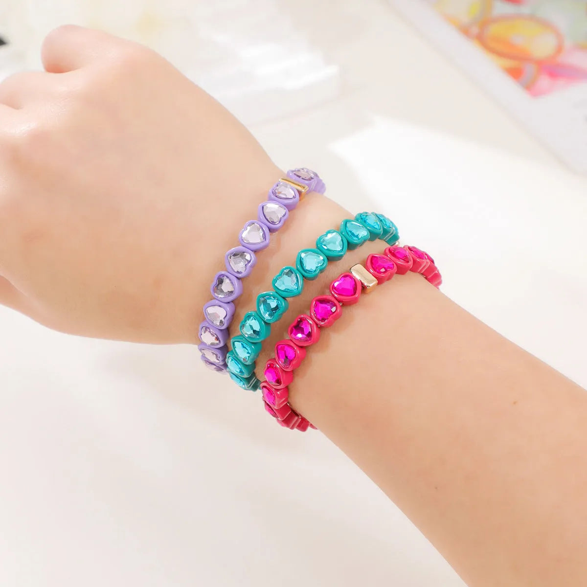 Rainbow coloured alloy heart charm on a stretch bracelet with a diamond-effect finish.