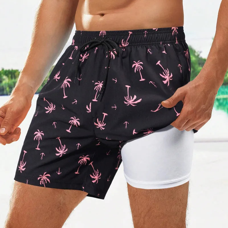 Man wearing loose green floral print boxer-style swimming trunks at the beach.