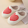 Women's plush slippers with cartoon love design, showing round toe and non-slip PVC sole.