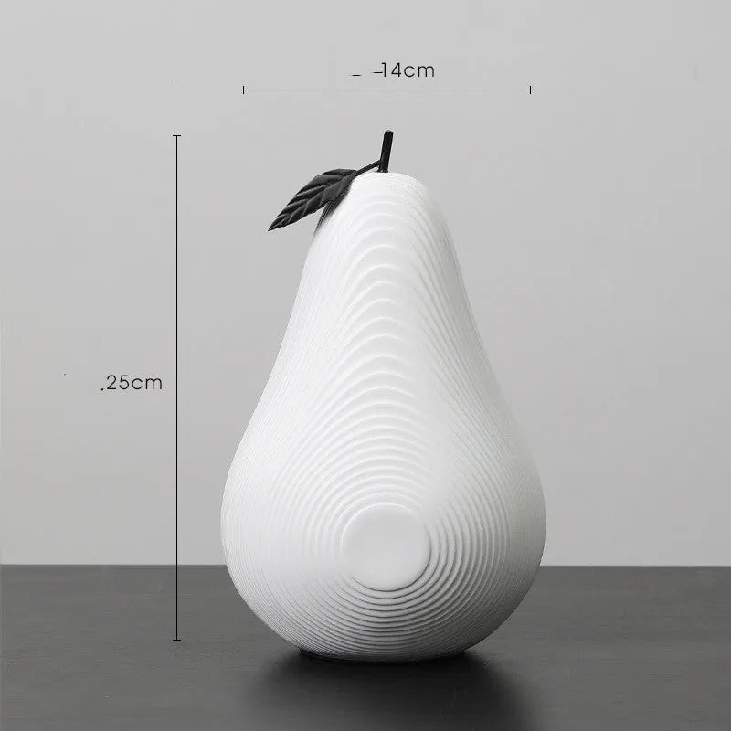 Black and white resin apple and pear ornaments on a wooden table