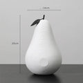 Black and white resin apple and pear ornaments on a wooden table