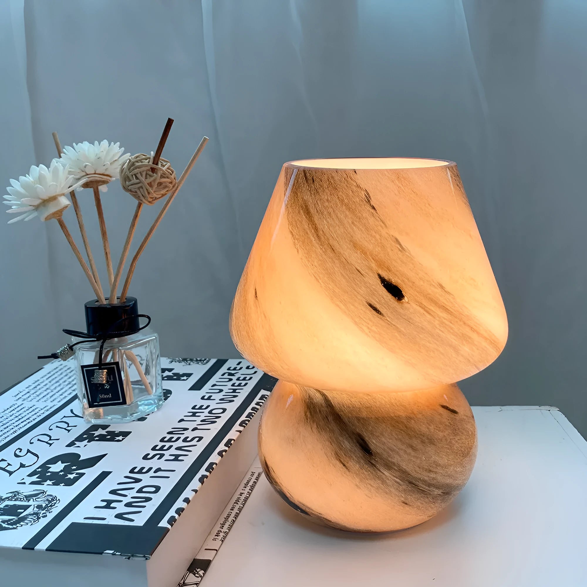 Handmade glass mushroom table lamp in colour finish, 15cm diameter, on a bedside table.