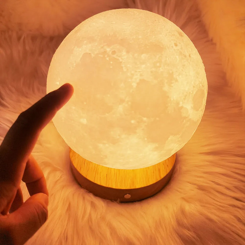 Rotating sleeping moon night lamp on wooden base showing three-colour light options.