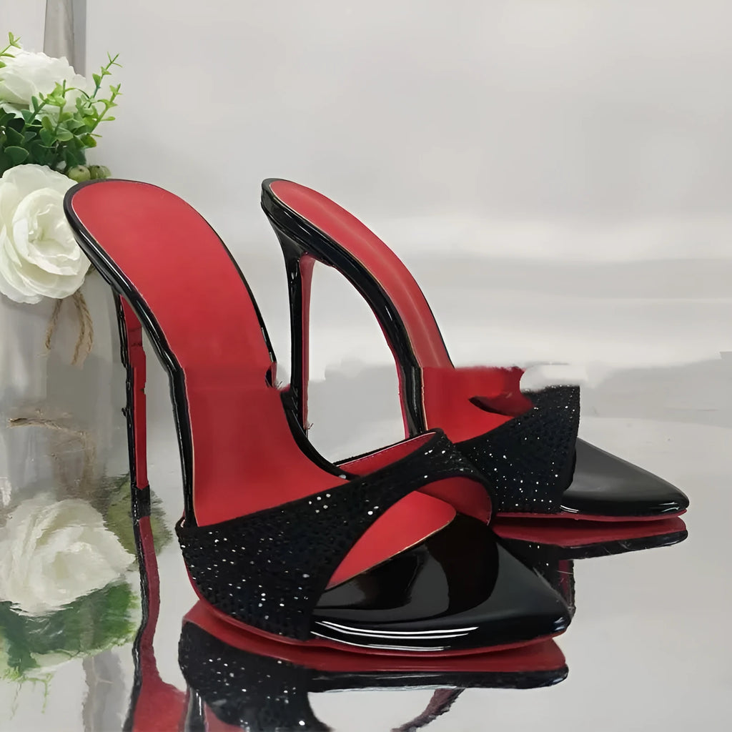 Black rhinestone ankle-strap open toe sandal with super high heel and pointed toe on white background