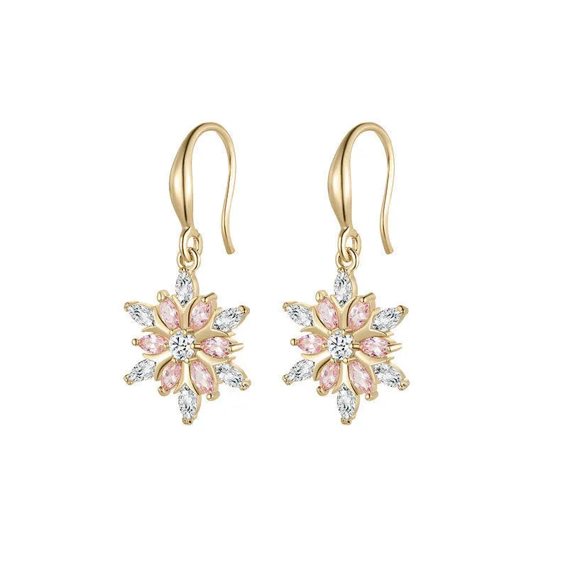 Gold alloy snowflake drop earrings with clear zircon centre on a white background