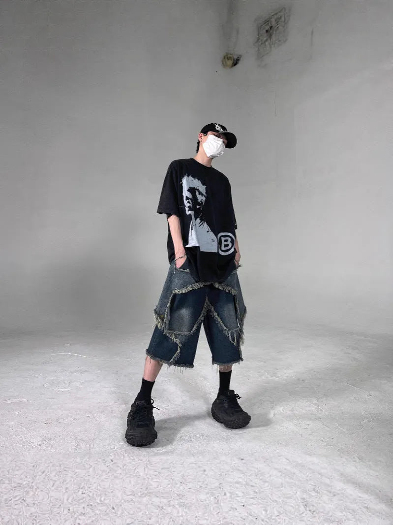 Blue denim shorts with a frayed hem and a large five-pointed star design on the leg, shown on a model.