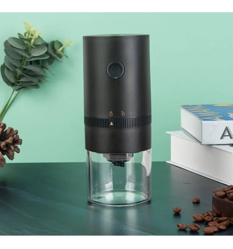 Black portable electric coffee grinder with transparent chamber showing coffee beans, USB-C charging port visible