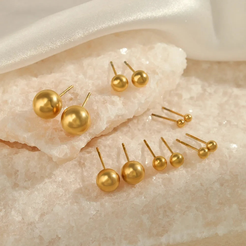 Simple stainless steel stud earrings with geometric sphere design in gold colour on white background