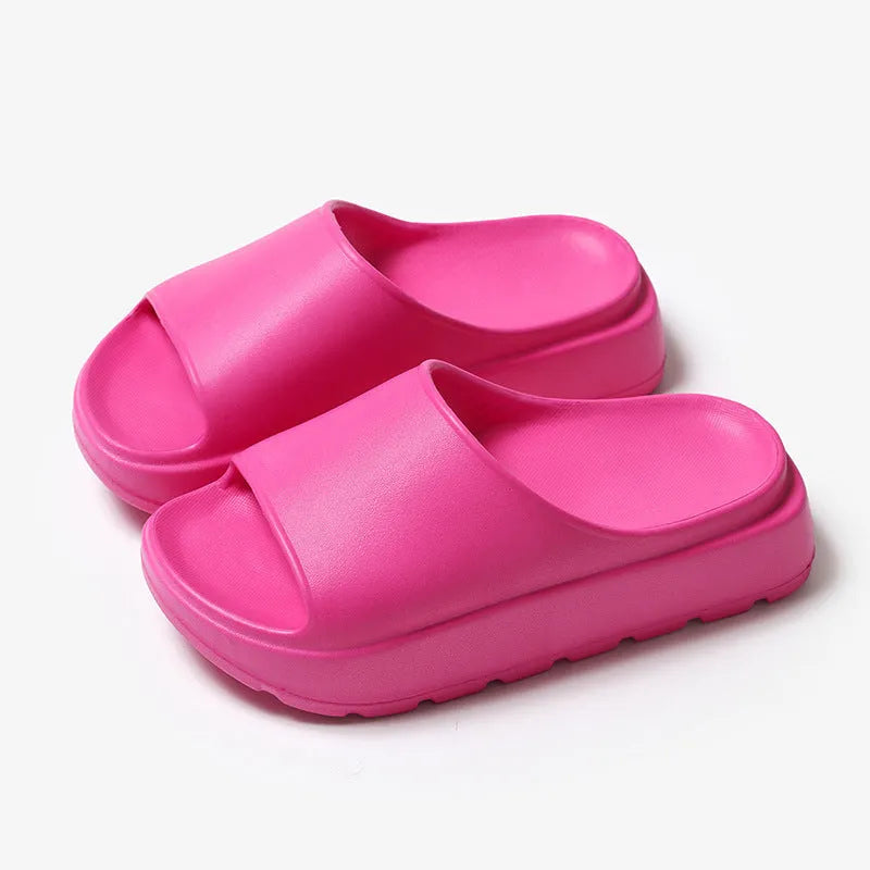 Women's beige open-toe beach slippers with a thick light-coloured sole on a wooden deck.