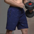 Man wearing loose grey printed polyester sports shorts on a beach.