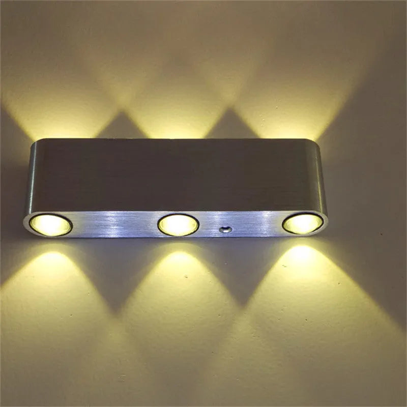 Silver aluminium rectangular LED wall lamp mounted on a wall, displaying multiple light colour options.