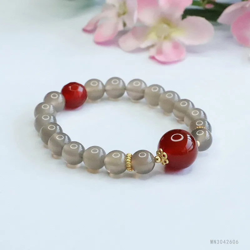 Close-up of a bracelet with smoky purple and red agate geometric beads on a white background.