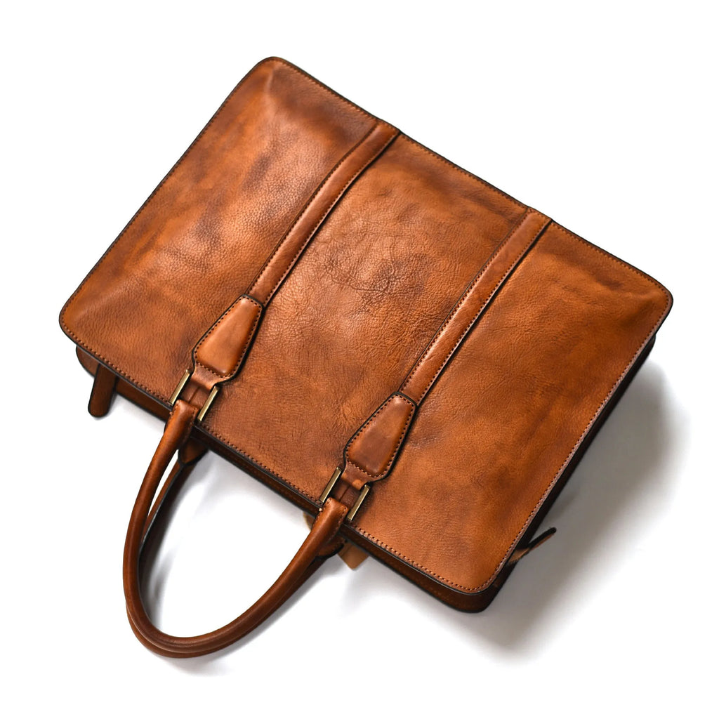 Men's brown leather retro style horizontal handbag with zipper, shown next to a 14-inch laptop for scale.