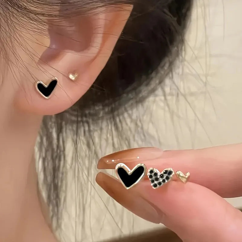 Three pairs of heart-shaped alloy earrings with electroplated finish in gold, black, pink or black and white