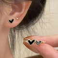 Three pairs of heart-shaped alloy earrings with electroplated finish in gold, black, pink or black and white
