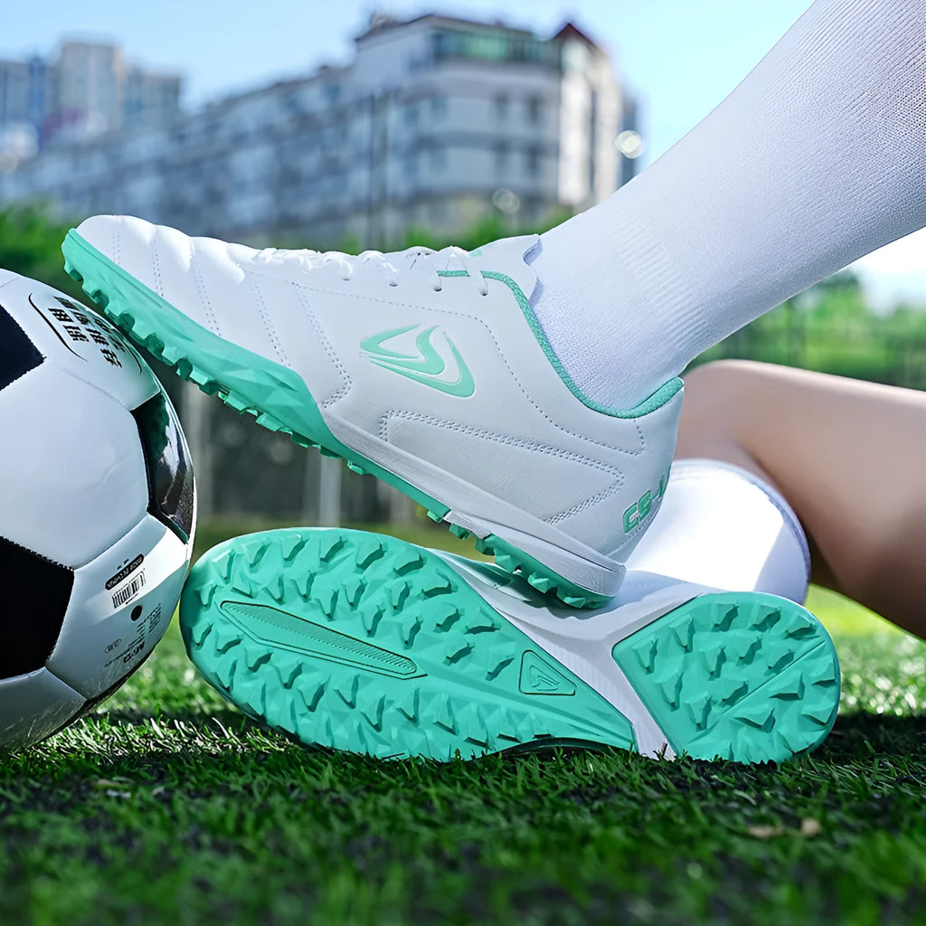 Low top football shoes with synthetic leather upper and rubber sole in black and white broken nails colour.