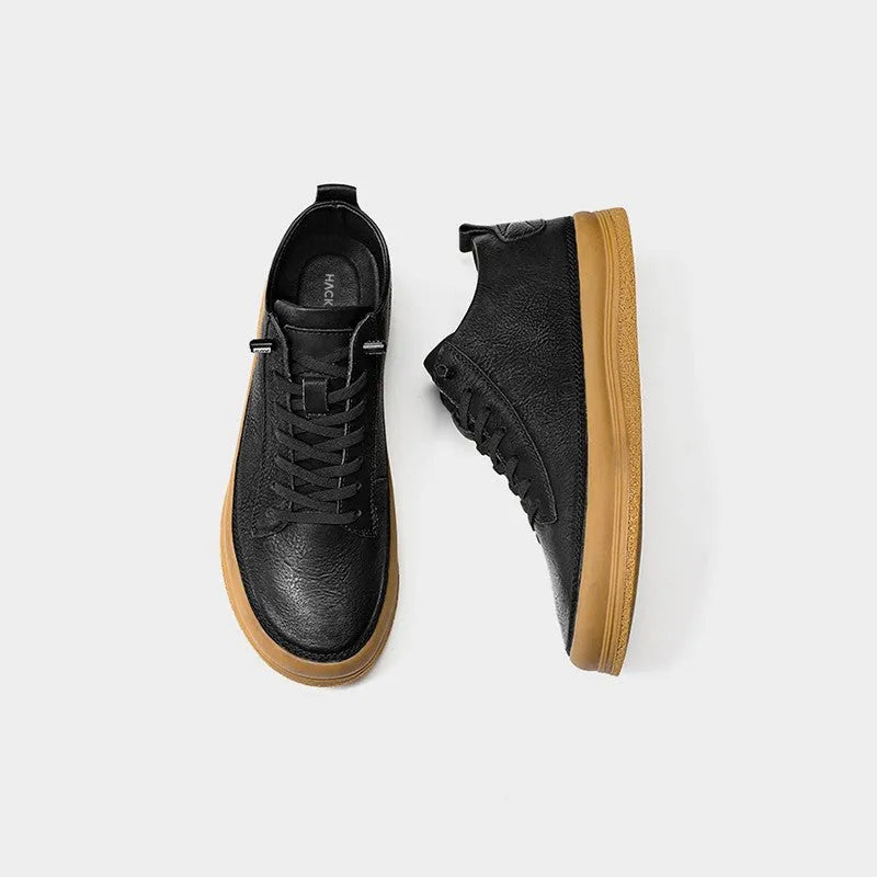 Men's black leather casual shoes with round toe and white flat rubber sole on a plain background