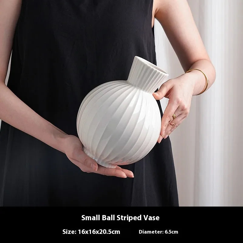 White ceramic vase with blue stripes in ball shape on wooden table