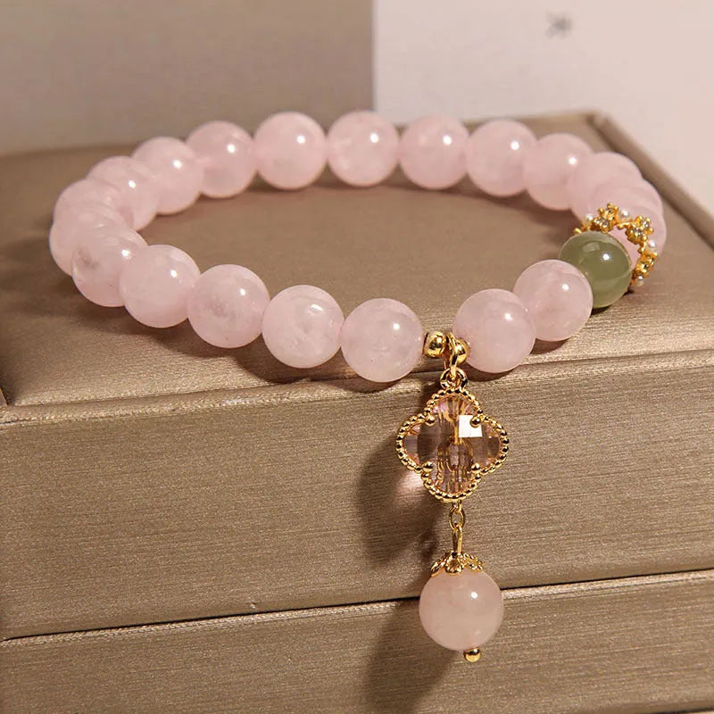 Pink crystal bracelet with a four-leaf clover pendant and rhinestone details on an alloy chain.