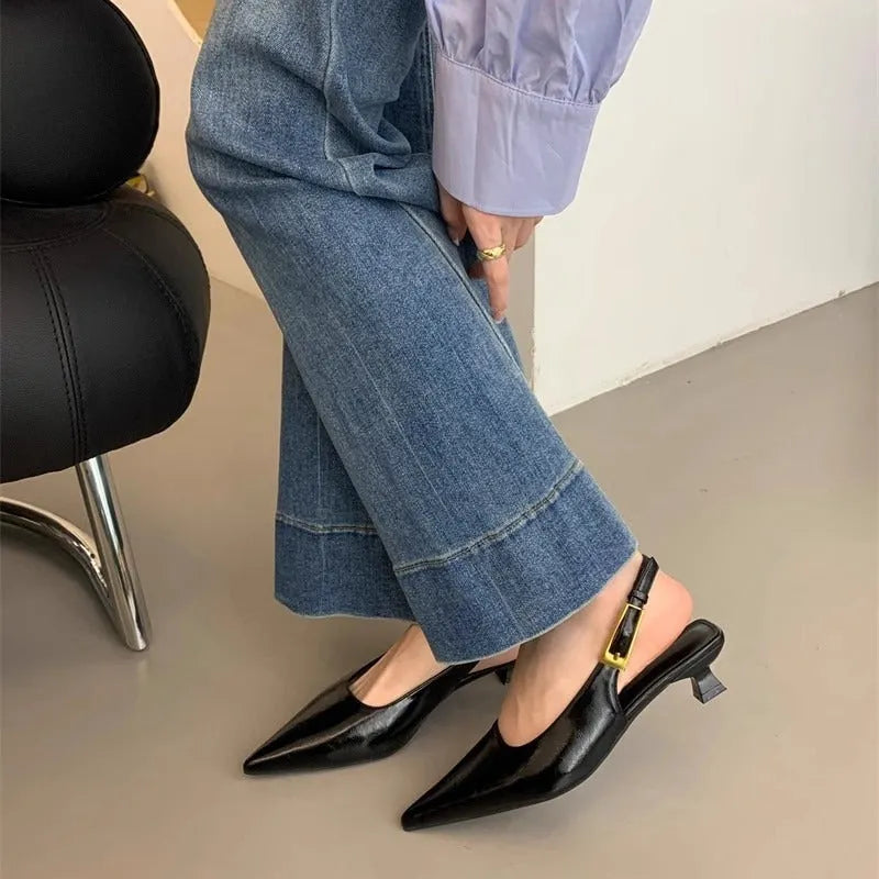 Women's black pointed leather low-heel shoes with thin decorative straps and a rubber sole.