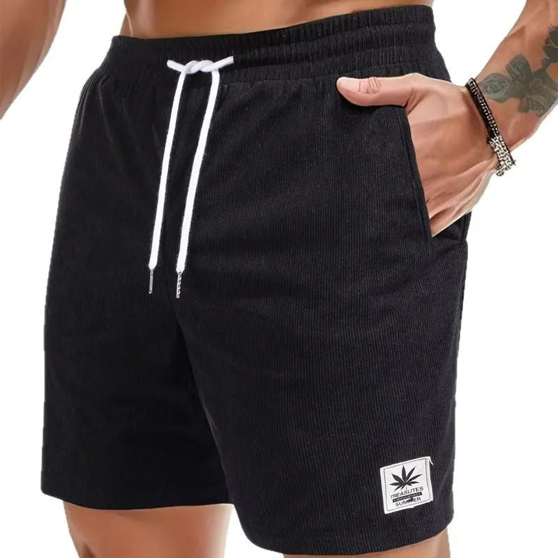 Man wearing grey straight-cut elastic drawstring summer shorts on a beach.