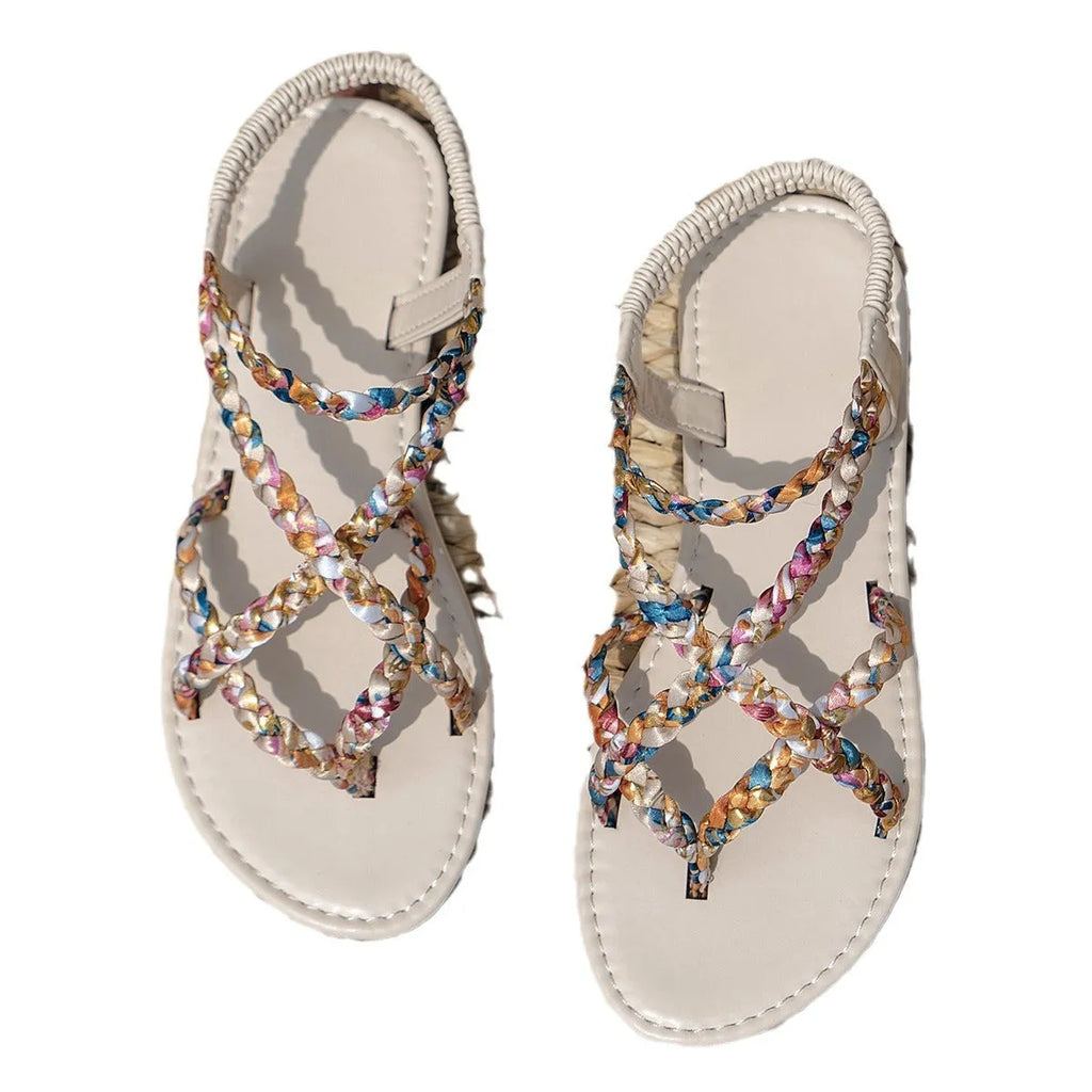 A pair of flat, low-top sandals with a cloth upper and elastic band closure across the instep.